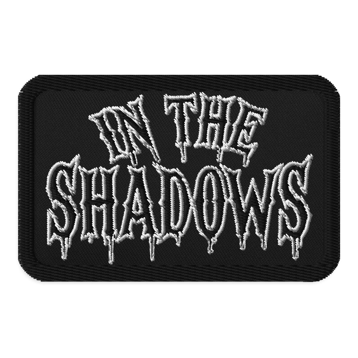 Rectangle embroidered patch featuring In The Shadows Iron On, front view