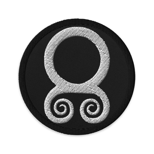 Circular embroidered patch featuring White Troll Cross, front view