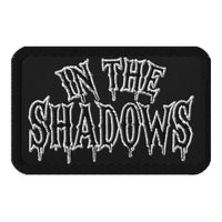 Rectangle embroidered patch featuring In The Shadows Iron On, front view