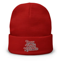 Red cuffed beanie with Dark Truth Revealed True Crime embroidered artwork, front view