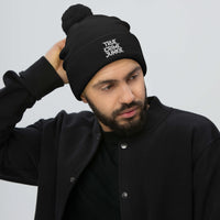 Black pom-pom beanie with True Crime Junkie embroidered artwork, front view