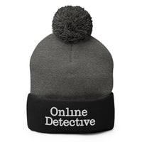 Black pom-pom beanie with Online Detective embroidered artwork, front view