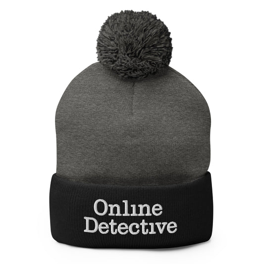 Black pom-pom beanie with Online Detective embroidered artwork, front view