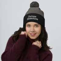 Black pom-pom beanie with Online Detective embroidered artwork, front view