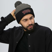 Black pom-pom beanie with Twisted Horror Carnival embroidered artwork, front view