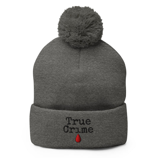 Gray pom-pom beanie with True Crime Blood Drop embroidered artwork, front view