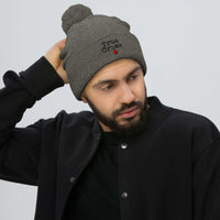 Gray pom-pom beanie with True Crime Blood Drop embroidered artwork, front view