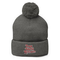 Gray pom-pom beanie with Dark Truth Revealed embroidered artwork, front view