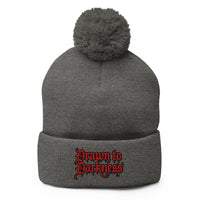 Gray pom-pom beanie with Drawn to Darkness embroidered artwork, front view
