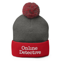 Red pom-pom beanie with Online Detective embroidered artwork, front view