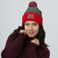 Red pom-pom beanie with Death Dealer True Crime embroidered artwork, front view
