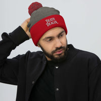Red pom-pom beanie with Death Dealer True Crime embroidered artwork, front view