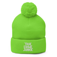 Green pom-pom beanie with True Crime Junkie embroidered artwork, front view