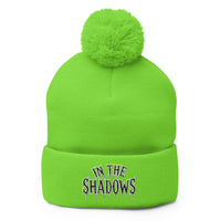 Green pom-pom beanie with In The Shadows embroidered artwork, front view