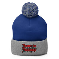 Gray pom-pom beanie with Drawn to Darkness embroidered artwork, front view